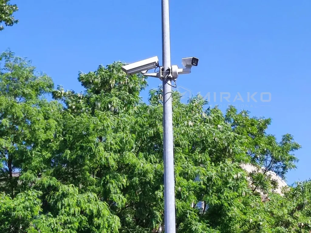 Starsza kamera analogowa w obudowie i kamera IP PTZ 4 MP podłączona przez istniejący przewód koncentryczny.