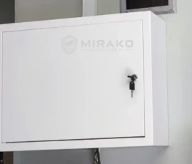 Rejestrator i switch PoE schowane w metalowej, zamykanej szafce.
