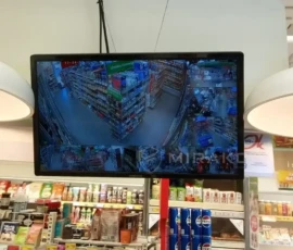 Monitor podglądu kamer zawieszony nad stanowiskiem sprzedawcy w sklepie Żabka